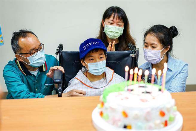 遭小货车辗压重伤的宜兰县王姓男童，今天在王父（左）、王母（右）、阿姨（后）的陪同下出院，阳明交通大学附设医院送上特制蛋糕欢庆他出院重生。（李忠一摄）