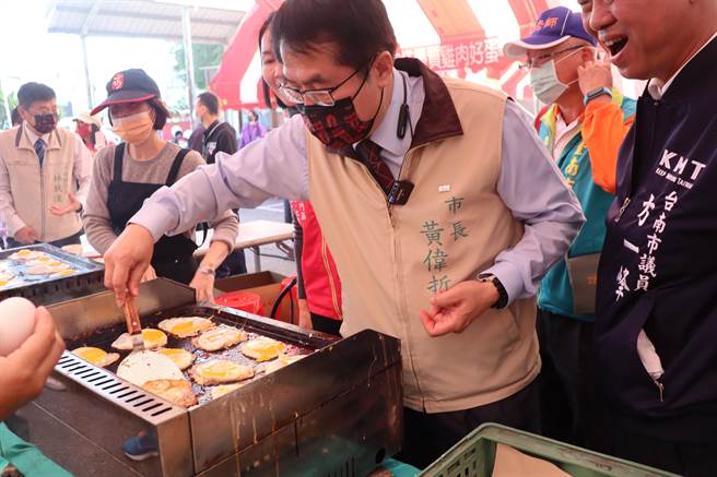 台南市长黄伟哲（前）参加西港胡麻节活动，亲自煎麻油鸡蛋。（刘秀芬摄）