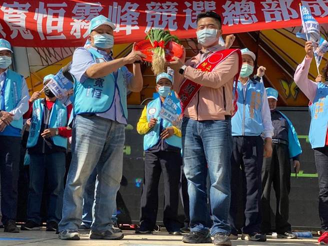 台中市第二选区立委补选，国民党参选人顏宽恒（右）5日成立雾峰竞选总部，大甲镇澜宫董事长顏清标（左）为其子上送上象徵「冻蒜」的「青蒜」。（读者提供／张妍溱台中传真）
