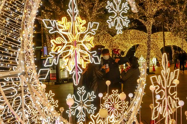 台北101大樓廣場裝設漂亮的LED耶誕燈飾，吸引許多上班族駐足拍照。（黃子明攝）