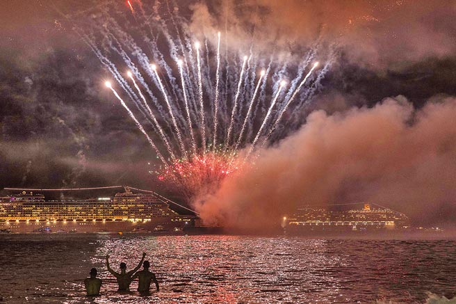 里約因新冠疫情連續第二年取消跨年活動。圖為2018年1月1日，巴西里約熱內盧科帕卡巴納海灘，人們觀看焰火表演迎新年。（新華社）