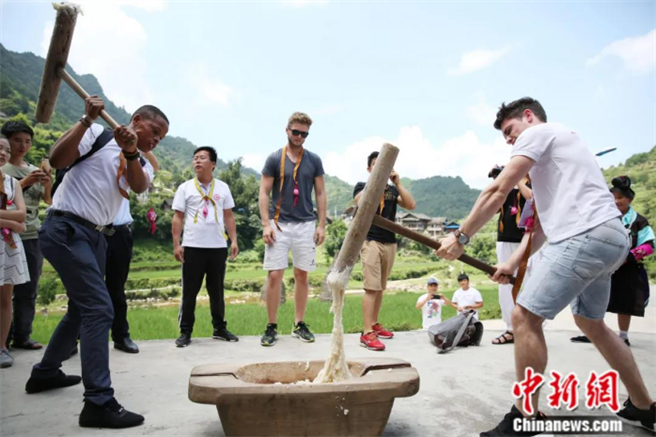 2017年7月，来自德国和南非两所大学的师生一行17人来到贵州省开展夏令营活动。图为海外学生在苗寨体验打糍粑。（中新社）