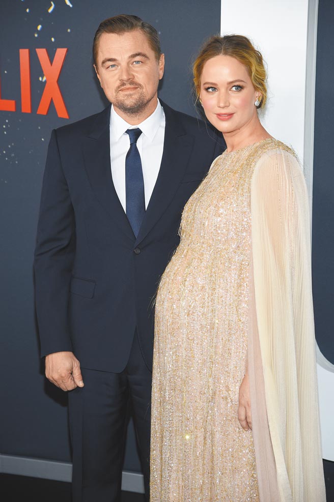 珍妮佛勞倫斯（右）昨挺孕肚與李奧納多狄卡皮歐盛裝出席《千萬別抬頭》首映會。（美聯社）