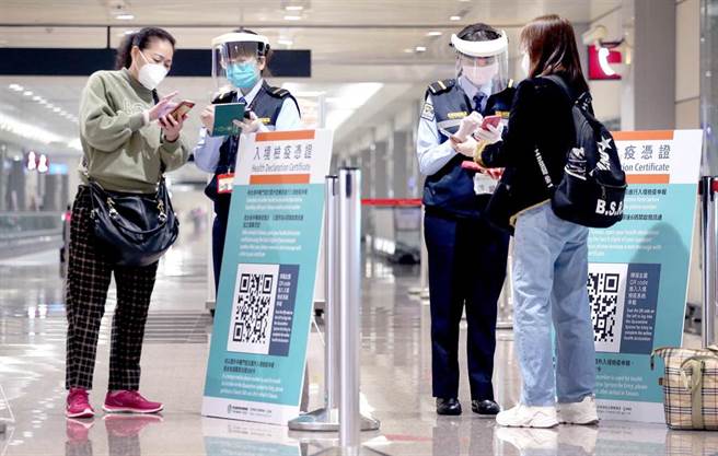 指揮中心證實，1名8日自史瓦帝尼入境的本國籍女性確定感染Omicron，為該變異株侵台首例。在桃園機場入境管制區內，防疫人員協助旅客上網登錄入境檢疫資料（圖中非新聞當事人）。（范揚光攝）
