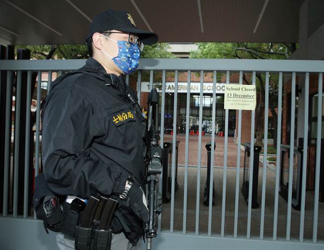 台北美國學校驚傳收到不明份子的恐怖威脅，校方緊急發出通知書13日預防性停止上課一天，士林分局刑警荷槍實彈站在校門警戒。（陳怡誠攝）