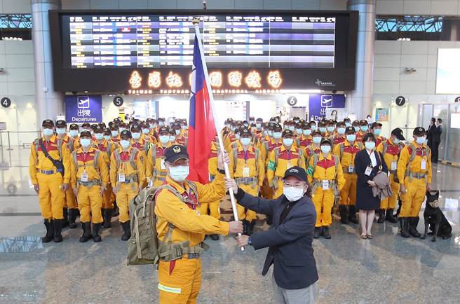 消防署首次演练搜救队搭乘包机出国值勤的假想状况。在第二航厦出境大厅内，政务委员张景森（前右）授旗给搜救队。（范扬光摄）