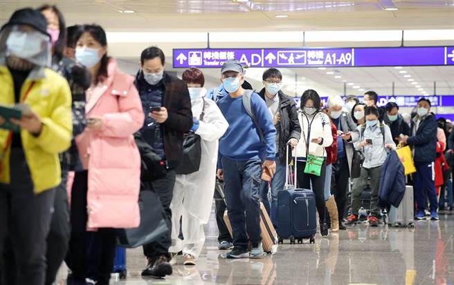 春节检疫政策14日首日上路，吸引大批民眾返台，据中央流行疫情指挥中心统计，选择「7＋7」专案的旅客占多数，在桃园机场入境管制区内，刚下机的旅客排队查验入境检疫资料。（范扬光摄）
