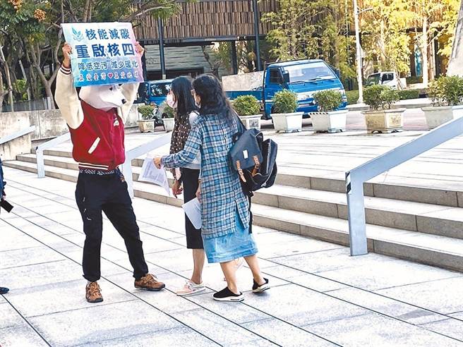 图为环团14日在台中市议会广场为「藻礁投同意」催票时，一名头戴北极熊头套的民眾，手持「核能减碳、重启核四」，与环团一度发生争议。（卢金足摄）