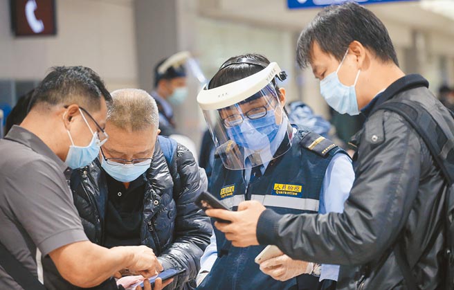 桃园发生防疫旅馆群聚感染，疫情指挥中心16日宣布，强化春节入境专案筛检次数。图为桃机防疫人员协助入境旅客上网登录。（范扬光摄）