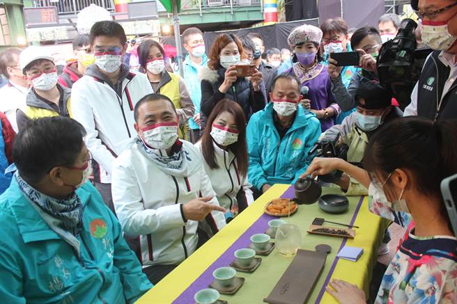 新北市长侯友宜到摊位品茗最爱的东方美人茶，笑言在新北市欢乐耶诞城非饮食专区不能脱口罩吃东西，让他闻香心痒痒却不能喝。（陈慰慈摄）