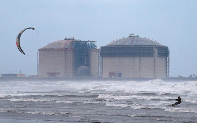 1位风筝衝浪玩家17日在三接工地附近乘风踏浪，远方为兴建中的两座储气槽。（范扬光摄）