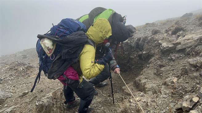 山友李女晕倒，高山协作前往背负患者至山屋取暖。（台中市消防局提供）