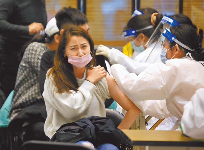 指挥中心公布12月24日起与第二剂间隔满5个月的18岁民眾，都可以自行到诊所预约施打第三剂，北车疫苗接种站将延长接种服务至12月29日。图为民眾21日在台北火车站接种疫苗，露出痛苦表情。（陈君玮摄）