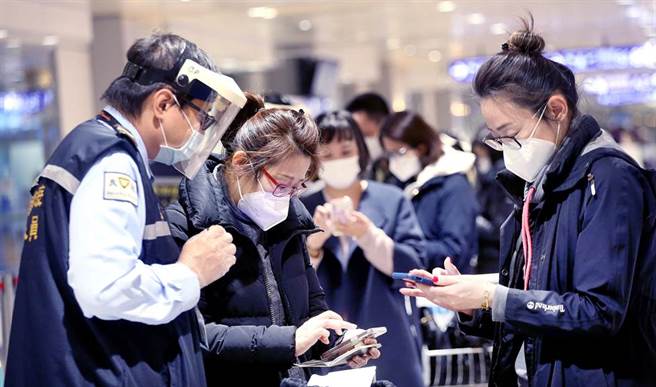 中央流行疫情指挥中心24日公布国内新增20例新冠肺炎境外移入确定病例，在桃园机场入境管制区内，防疫人员协助刚下机的旅客上网登录入境检疫资料。（范扬光摄）（图中非新闻当事人）
