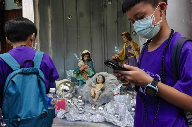 台北市天主教聖家堂今年聖誕裝置「疫苗馬槽」很特別，針筒內設置耶穌在馬槽誕生情景，剛降生的耶穌手上拿著小針筒與口罩，陪伴在旁的馬利亞、約瑟全都戴上口罩。（黃子明攝） 