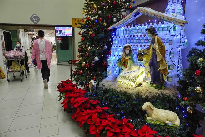 由天主教會創辦的耕莘醫院，在聖誕前夕於院內文藝走廊設置馬槽，屋頂以莫德納、BNT、AZ等疫苗包裝盒構成，馬槽牆面與柱子用酒精消毒液及生理食鹽水空瓶組成，向民眾宣導防疫。（黃子明攝） 