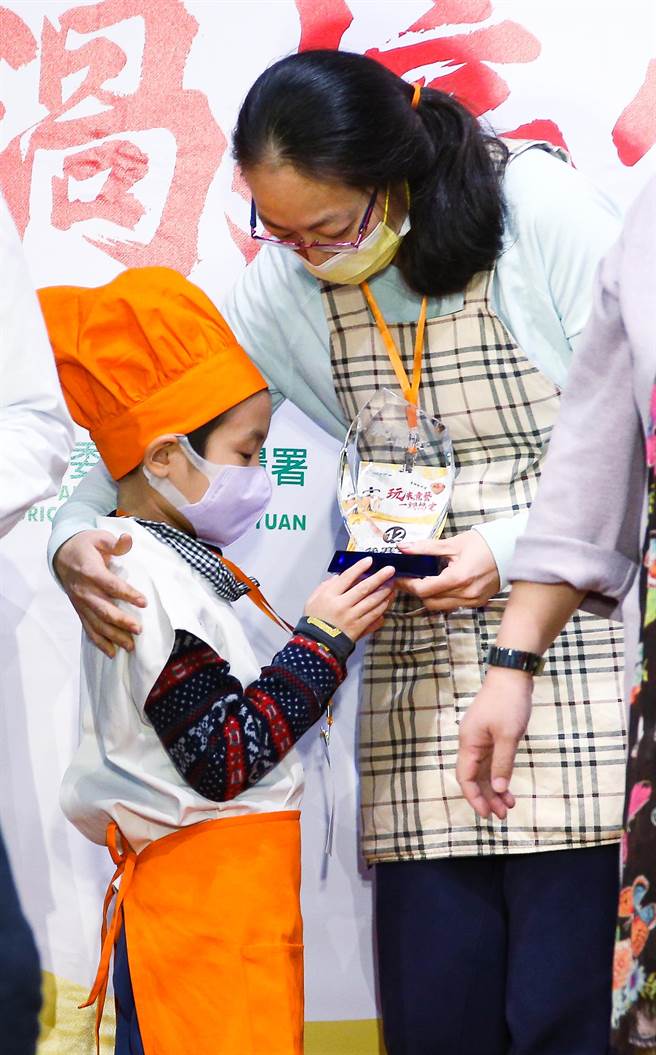 「玩米煮艺一锅搞定-电锅饭料理」竞赛，一名小朋友和妈妈一同制作料理获奖后， 兴奋直盯着手里的奖座。（罗永铭摄）