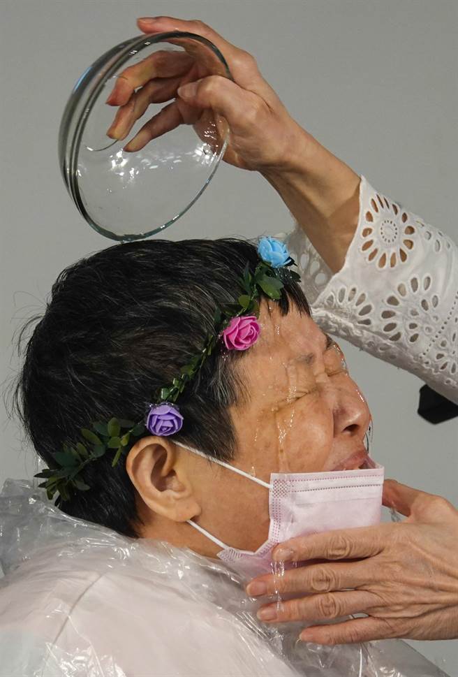 年長教友乘坐輪椅接受牧師施以點水禮完成受洗。（黃子明攝）