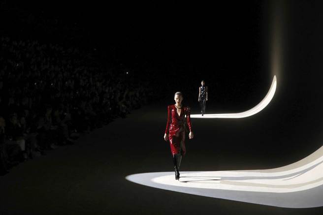 于SAINT LAURENT 秀场上，模特以金色项炼、过膝长靴展现酷帅风格。（美联社）