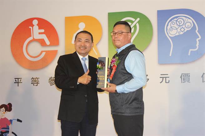 新北市长侯友宜表扬获得模范身心障碍者家属奖的涂文芳，他有2位罹患罕见疾病的儿子，1个荣获2021总统教育奖。（陈慰慈摄）