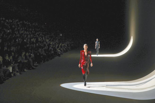 SAINT LAURENT秀场上，模特以金色项炼、过膝长靴展现酷帅风格。       （美联社）