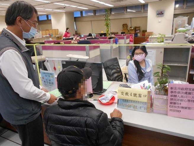 庄姓妇人担任里长之先生(戴帽者)至新北分署向书记官(站立者)办理分期缴纳，于新北市政府交通事件裁决处服务窗口缴纳部分款项（新北分署提供／戴上容新北传真）