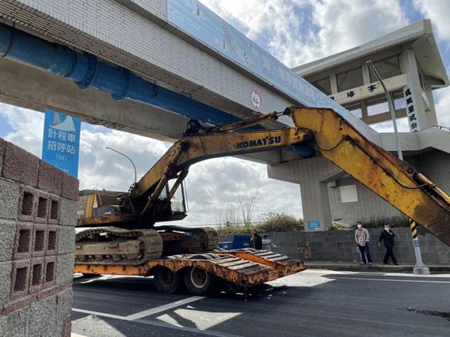 一輛拖車載運挖土機2日行經澎湖水族館連接抽水站的景觀空橋，疑因未調降油壓伸縮桿，導致卡在橋下，動彈不得；空橋有無受損，水試所將請結構技師進行勘驗，再向業者求償。（水試所澎湖海洋生物研究中心提供/中央社）