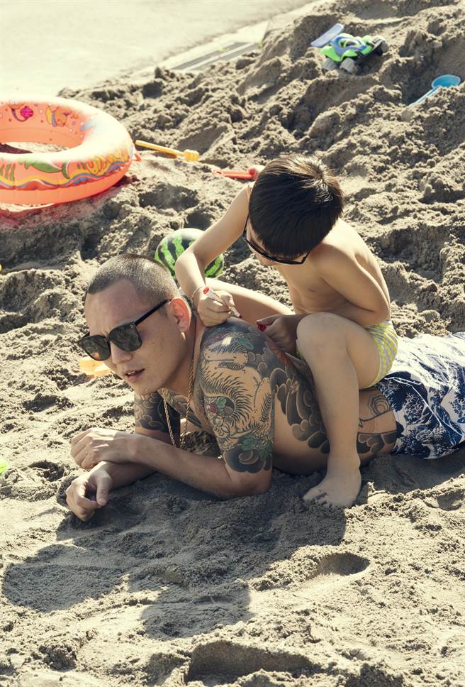 春风（左）让小演员姜仁在他的刺青上作画。（许杰辉提供）