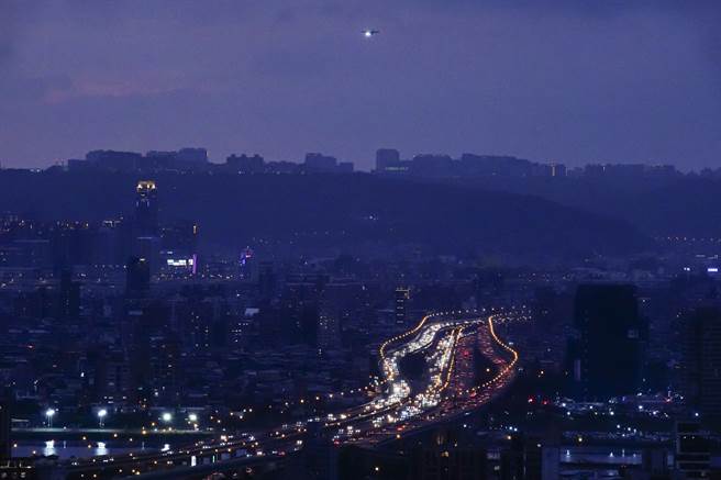 劍潭山高處遠眺國道一號，有如兩串不同顏色寶石項鍊，但車流大致順暢，空中也有班機準備降落松山機場。（黃子明攝）