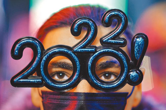 全球在Omicron变种病毒疫情阴影下步入2022年。图为一名美国民眾戴口罩参加跨年活动。（路透）
