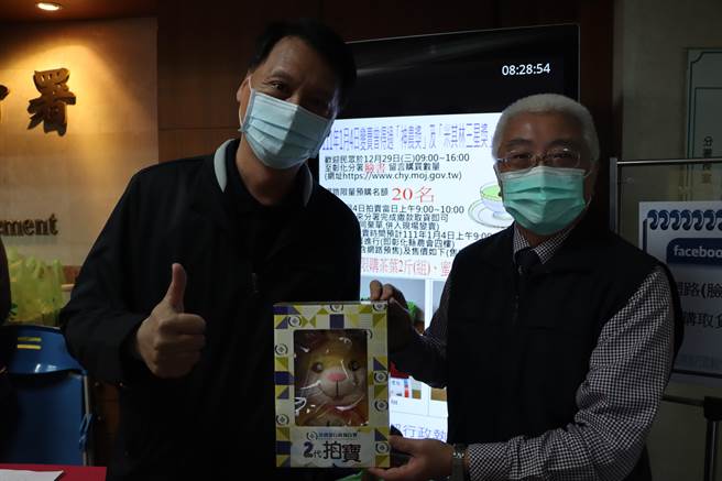 彰化分署長謝道明（右）親自頒發分署吉祥物「拍寶」給拔得頭籌，第一個完成網路預購登記的彭姓彰化市民（左）。（彰化分署提供／謝瓊雲彰化傳真）