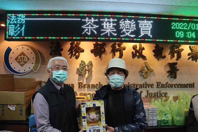 第一個到場現場排隊搶購的民眾（右）今天一早從台中出發，7點多就到場排隊，彰化分署長謝道明（左）親自頒發分署吉祥物「拍寶」表示感謝。（彰化分署提供／謝瓊雲彰化傳真）