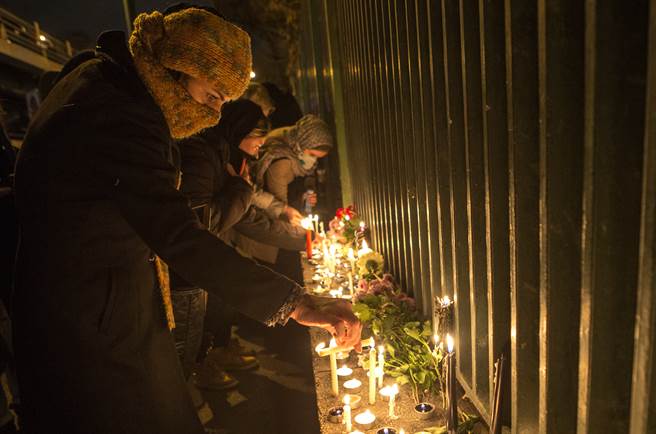 民眾在烏克蘭失事客機遇難者的悼念儀式上點燃蠟燭寄託哀思。(圖／新華社)