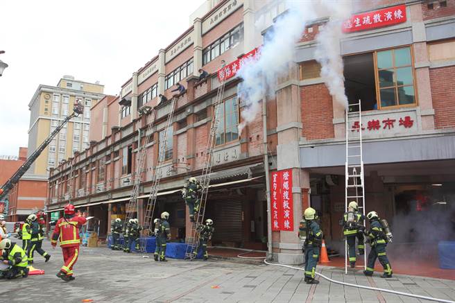 「2022臺北年貨大街消防演習」，圖為「架設關東梯與雙節梯實施人命救助」項目演練，消防員在火災現場架梯搶救。（張鎧乙攝）