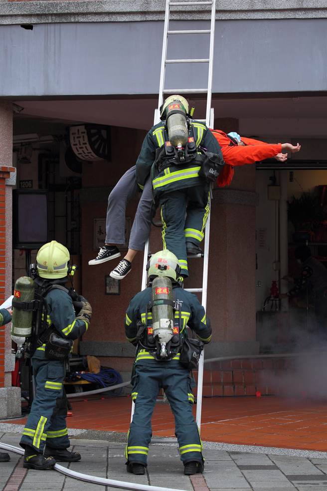 「2022臺北年貨大街消防演習」，圖為「架設關東梯與雙節梯實施人命救助」項目演練，消防員在火災現場架梯搶救。（張鎧乙攝）
