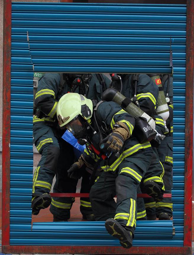 「2022臺北年貨大街消防演習」，圖為模擬年貨大街發生火警意外，消防員破門進入搶救。（張鎧乙攝）