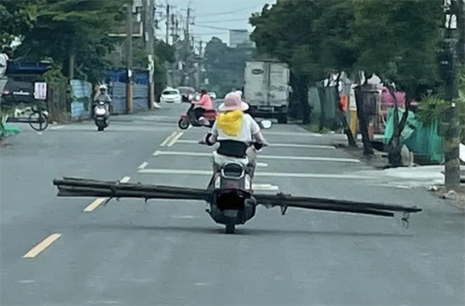 民眾在高雄目击，一名阿嬷没戴安全帽就骑机车，还违规载运超长的木头，造成他人用路危机。（翻摄爆料公社App）