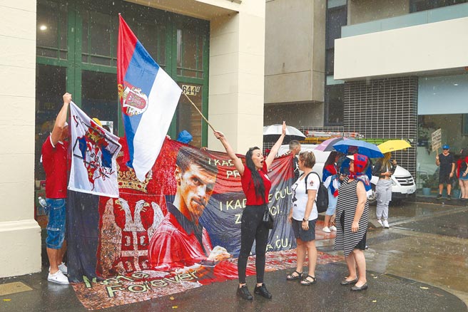 现役世界球王乔柯维奇，寻求医疗豁免入境参加澳洲网球公开赛未果，不但震动网坛，也让塞尔维亚、澳洲两国关系紧张。图为乔柯维奇的球迷在其下榻的饭店外挥舞旗帜、标语表达力挺。（美联社）