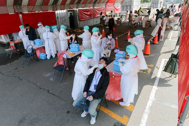 桃机员工排队做PCR採检，由于採检棒需整根深入鼻腔，员工表情显露不适。（陈麒全摄）