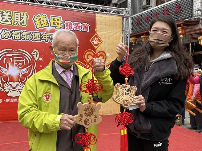 嘉義市議員戴寧搶購檜木好福氣錢母，嘉義城隍廟董事長賴永川送出錢母結緣。（廖素慧攝）