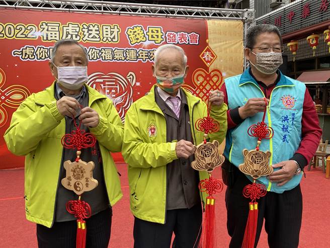嘉義城隍廟董事長賴永川送出限量版檜木錢母與搶購的信眾結緣。（廖素慧攝）