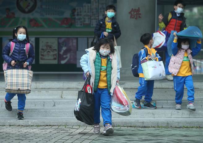 桃園境內有3所國小因有確診學生停課14天，市長鄭文燦於11日疫情說明記者會時宣布，國小提早1周放寒假，本周五（14日）最後1天上課。圖為學童提著大包小包上課物品離開學校。（陳怡誠攝）