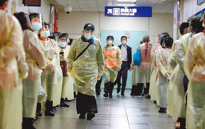 落地採检确诊数暴增，指挥中心放宽同班机可採2人1室。图为在第二航厦内，清洁人员上班前排队准备採检。（范扬光摄）