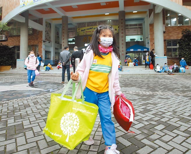 桃园机场新冠肺炎群聚升温，11日再传中坜区某国小附幼学童确诊，该校宣布即日起停课不停学2周，学童提着大包小包上课物品离开学校（见图），家长闻讯至学校接小孩。（陈怡诚摄）