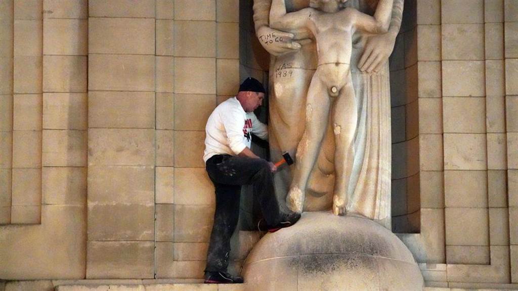 一男子拿鎚子敲打英国雕刻家艾里克‧吉尔所做的暴风雨主题雕像，因为吉尔生前有许多争议行为。图/BBC(photo:ChinaTimes)