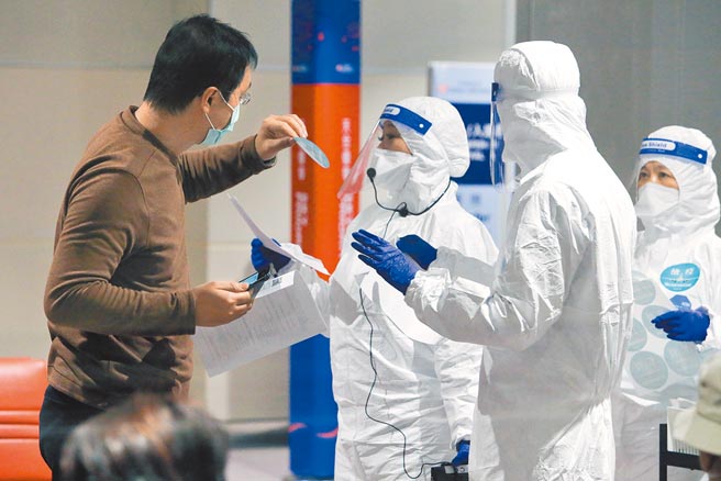 长程航班旅客须在机场採检阴性，才放行入境，旅客在下机后进入候机室，等待疾管署人员核对名单，在唱名后先贴上检疫识别贴纸，再依序採检、等待结果。（陈麒全摄）