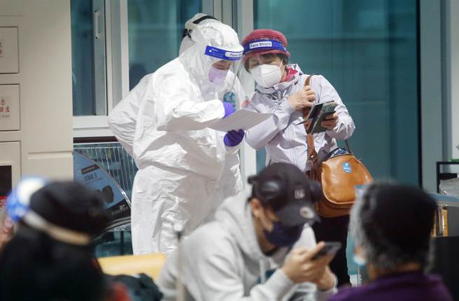 春節境外移入個案不斷增加。圖為桃園機場入境管制區的候機室內，檢疫人員正在確認長程航班入境旅客的名單身分。（范揚光攝）