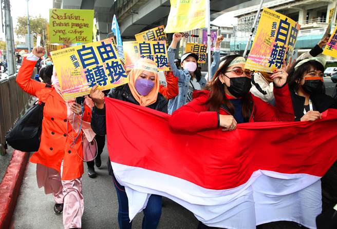 台湾移工联盟发起「我要自由转换」移工大游行，参与移工一手拿着印尼国旗一手拿着手机直播。（陈君玮摄）