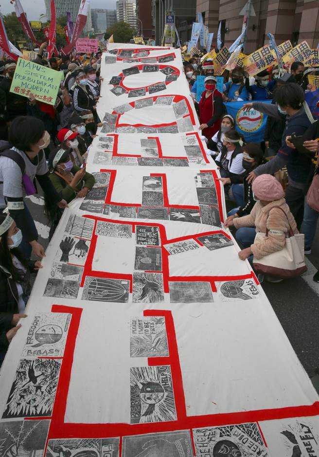 台湾移工联盟发起「我要自由转换」移工大游行，参与民眾合作展开一张巨幅FREEDOM布条，每个英文字母都是以移工朋友所绘制的版画作品拼贴而成。（陈君玮摄）