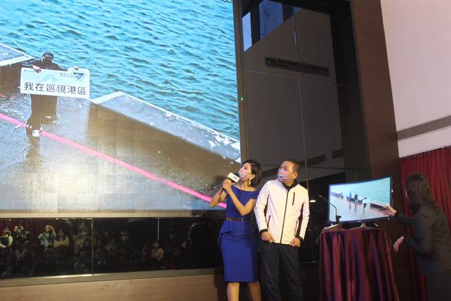 新北市长侯友宜试用智能渔港系统，远端广播提醒进入渔港危险区域的民眾远离开该区，后来发现是渔业处事先安排好的人员举牌称在巡视港区。（陈慰慈摄）